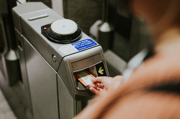 Person, die ein Zugticket in ein Drehkreuz einführt