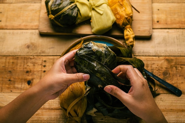 Person, die eine Tamale mit seinen Händen öffnet Tamale typisch mexikanisches Essen