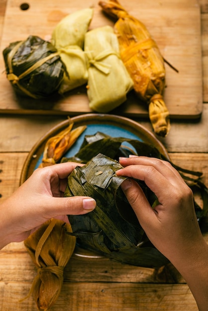 Person, die eine Tamale mit seinen Händen öffnet Tamale typisch mexikanisches Essen