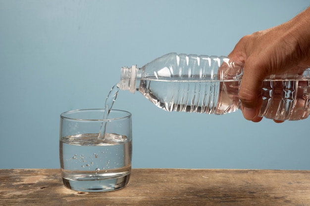 Person, die eine Tasse Wasser mit Haustierflasche füllt