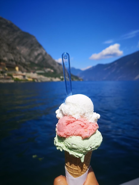 Foto person, die einen eiscreme-kegel im see hält