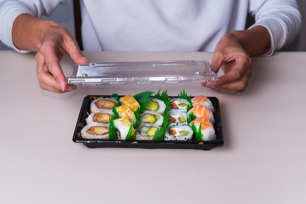Person, die Fast Food für die Lieferung von Sushi-Tabletts öffnet