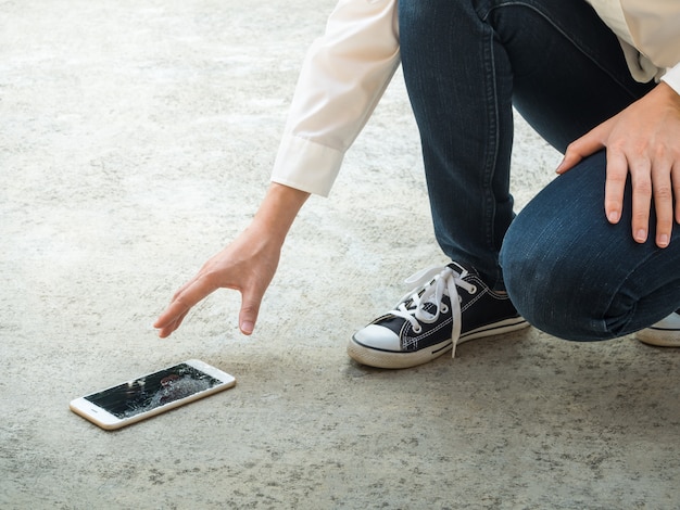 Person, die gebrochenes intelligentes Telefon des Bodens auswählt