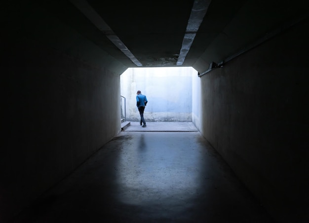 Person, die im dunklen Tunnelausgang geht