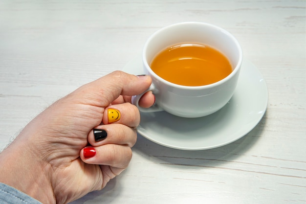 Foto person, die in einem café die tasse mit grünem tee füllt. ein mann mit lackierten nägeln. design von männlichen nägeln. männer maniküre.