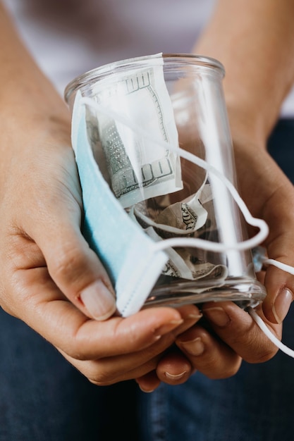 Foto person, die medizinische maske und klares glas mit geld hält