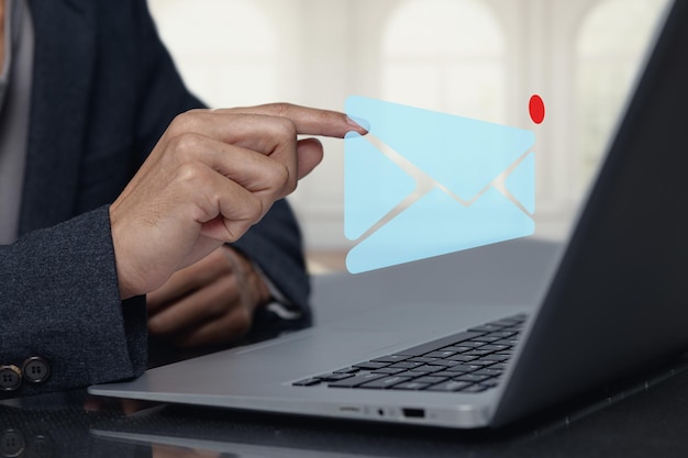 Person, die mit dem E-Mail-Symbol auf einem Laptop im modernen Office interagiert