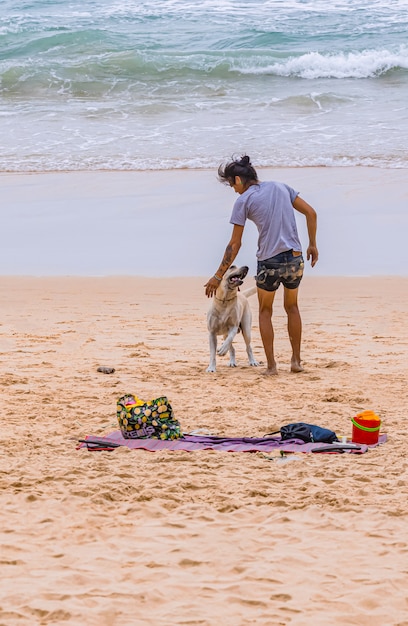 Person, die mit seinem Hund am Strand spielt