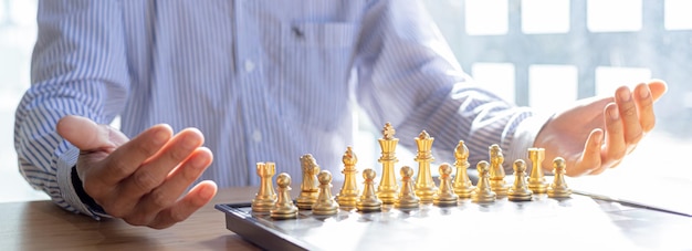 Person, die Schachbrettspiel spielt, Konzeptbild des Geschäftsmannes, das Schachfiguren wie Geschäftswettbewerb und Risikomanagement hält und Geschäftsstrategien plant, um Geschäftskonkurrenten zu besiegen.