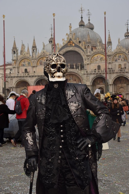 Person, die sich für den Karneval von Venedig mit Totenkopfmaske und schwarzem Anzug verkleidet hat