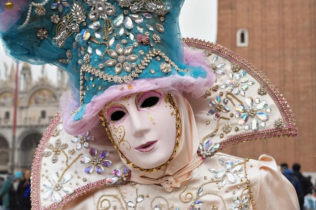 Person, die sich für den Karneval von Venedig verkleidet hat und ein Kostüm im französischen Stil mit Pastellfarben trägt
