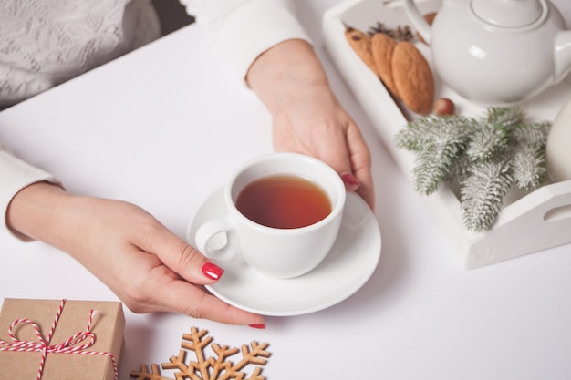 Person, die Tasse Tee mit Weihnachtsdekorationen hält