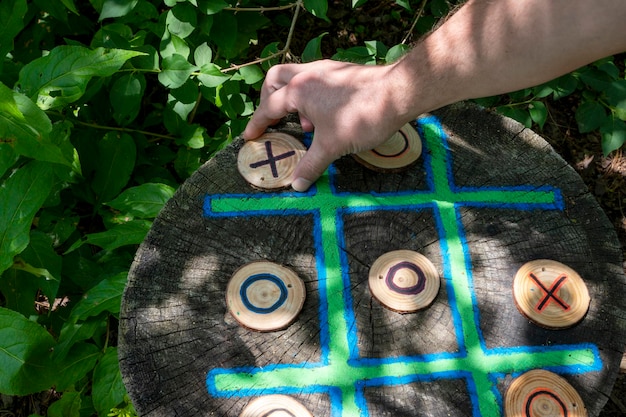 Person, die Tic Tac Toe aus Holz spielt. Umwelt natürliche Spiele