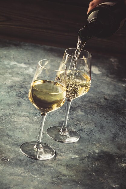 Foto person, die wein in ein glas auf den tisch gießt