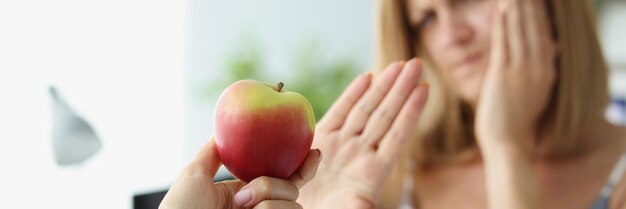 Person gibt Freund Apfel und Frau weigert sich wegen Zahnschmerzen zu essen