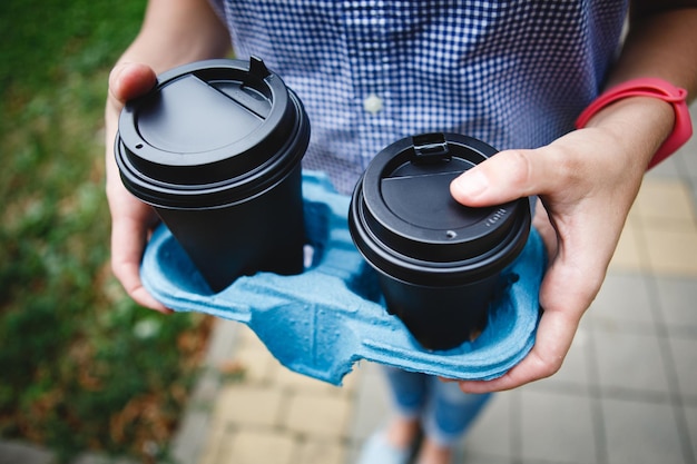 Person hält zwei Pappbecher mit Kaffee zum Mitnehmen