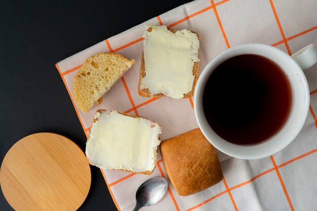 Person legte ein Stück Butter auf eine Scheibe Brot und eine Tasse Kaffee auf den Tisch, Frühstückskochen