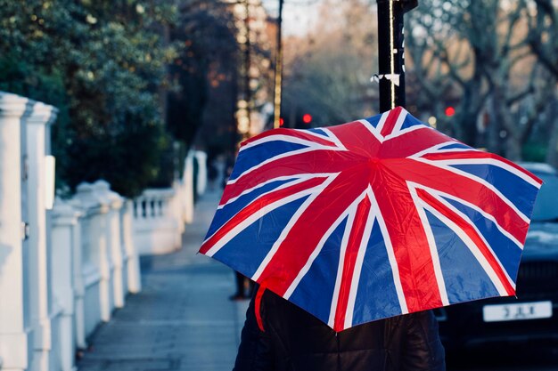 Foto person mit britischer flagge und regenschirm auf dem bürgersteig