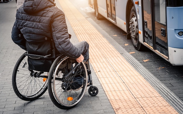 Person mit einer körperlichen Behinderung, die auf einen Stadtverkehr mit barrierefreier Rampe wartet