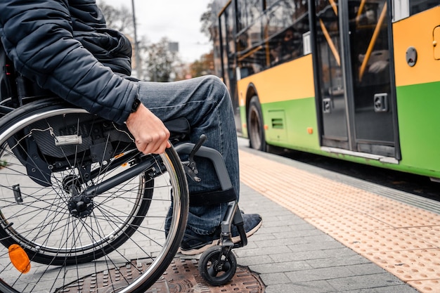 Person mit einer körperlichen Behinderung, die auf einen Stadtverkehr mit barrierefreier Rampe wartet