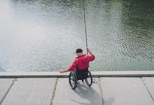 Person mit einer körperlichen Behinderung, die vom Angelsteg aus mit dem Rollstuhl angeln kann