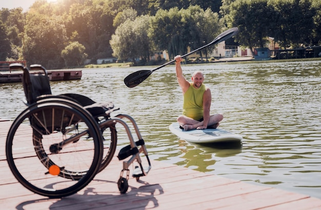 Person mit einer körperlichen Behinderung fährt auf einem SUP-Board