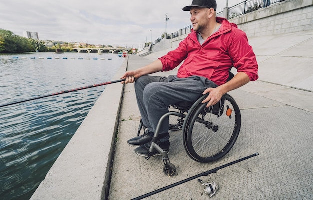 Person mit einer körperlichen Behinderung im Rollstuhl beim Angeln vom Angelsteg