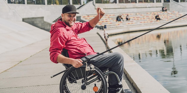 Person mit einer körperlichen Behinderung im Rollstuhl beim Angeln vom Angelsteg