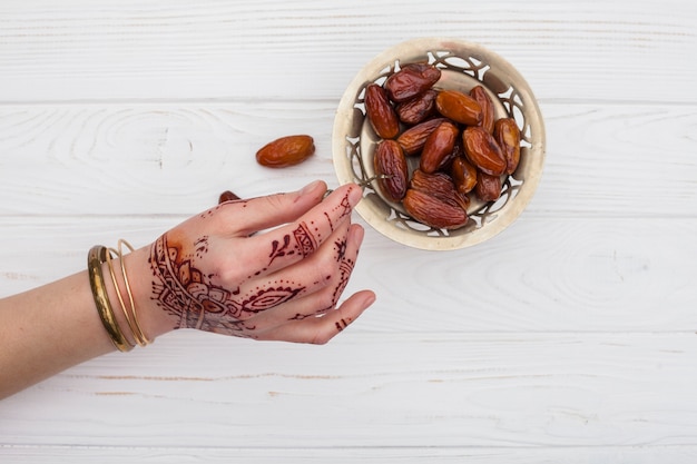 Person mit mehndi, die Frucht der getrockneten Dattel mit Gabel hält