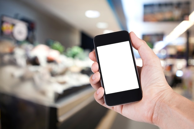 Person mit Smartphone weißen Bildschirmhalter zur Hand mit Markt Hintergrund im Supermarkt.