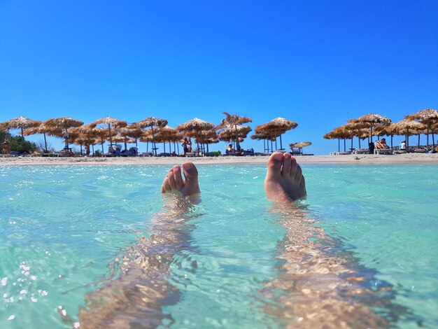 Person schwimmt im Pool vor klarem blauen Himmel