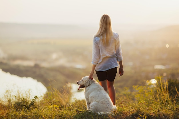 person und golden retriever-hund, die auf dem hügel stehen