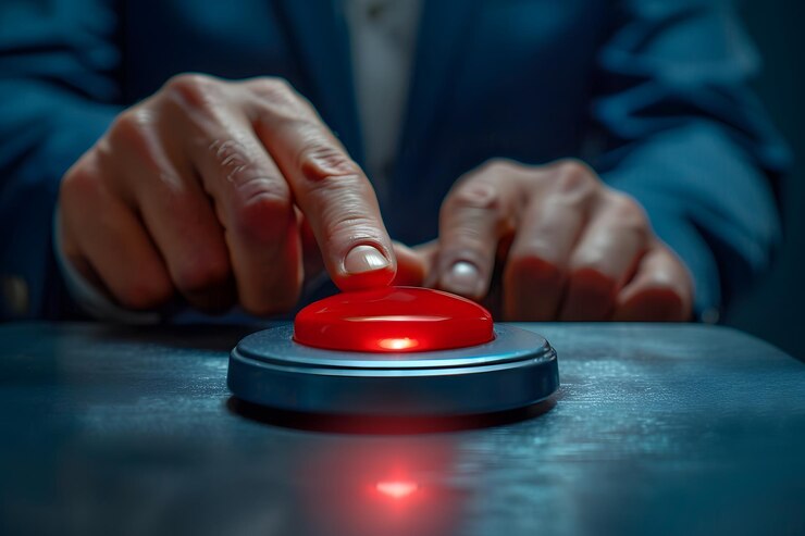 La persona activa el botón rojo bajo la luz roja en la mesa
