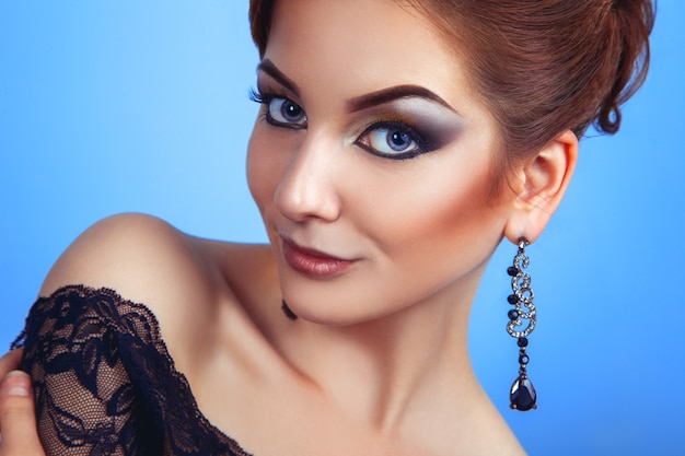 Persona adulta joven glamour con maquillaje en pared azul