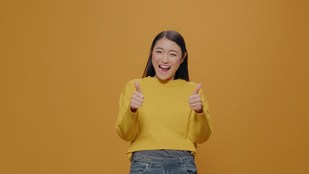 Persona alegre haciendo gestos de aprobación frente a la cámara mostrando aprobación y signo de acuerdo con los dedos, sonriendo en el estudio. Mujer complacida gesticulando bien y símbolo positivo.