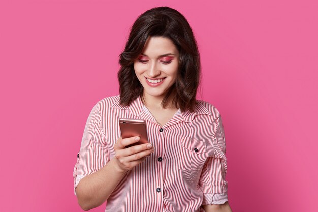 persona amada mira en el teléfono inteligente con una sonrisa en medio de la fotografía de retrato