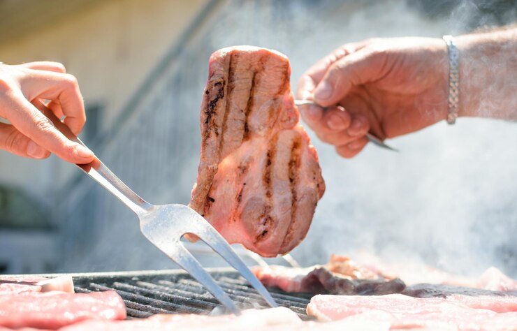 Una persona asando carne a la parrilla