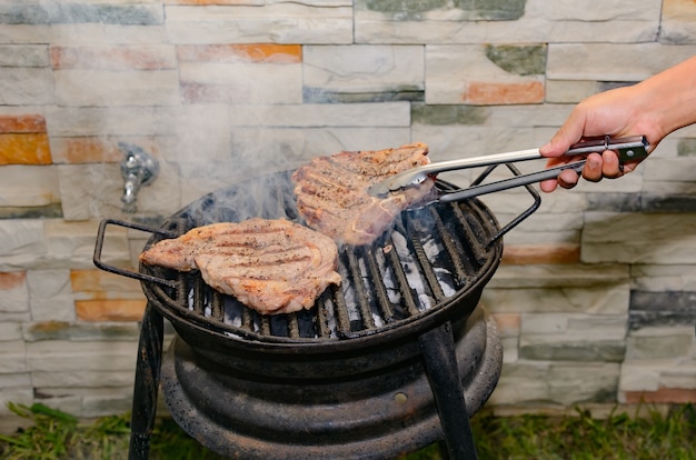 Persona asar carne en una parrilla casera Rosbif en el patio trasero de la casa