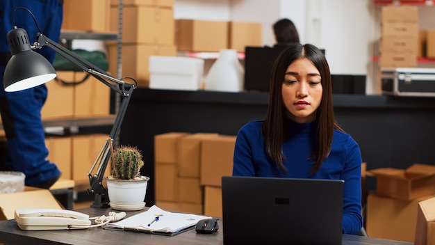 Persona asiática tratando de mejorar la calidad de los pedidos en la computadora portátil, verificando el stock de productos y la logística en la computadora. Joven empresario trabajando en el desarrollo de pequeñas empresas, enviando paquetes.