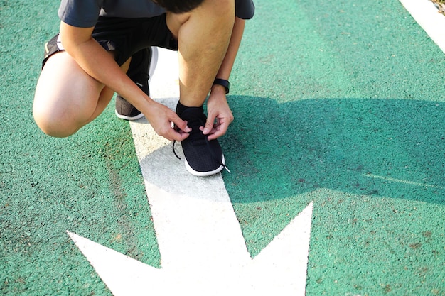 La persona se ata un zapato preparándose para correr o hacer ejercicios en la pista verde