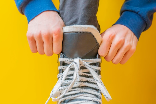 Persona atando cordones de zapatos en patines antes de patinar en una pista de hielo b