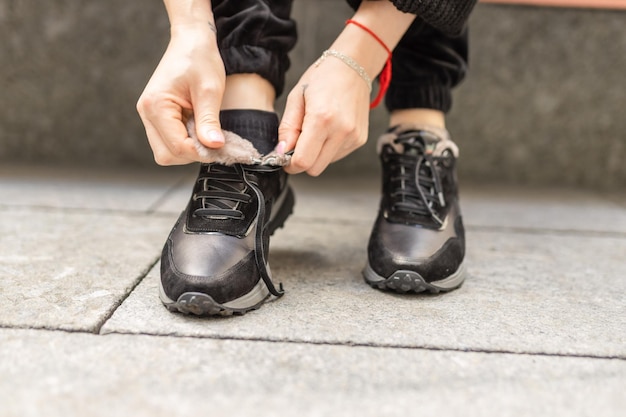 Una persona atándose los zapatos en una acera.