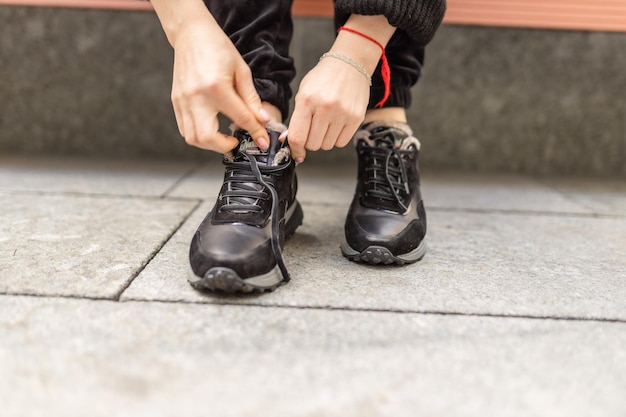 Una persona atándose los zapatos en una acera.