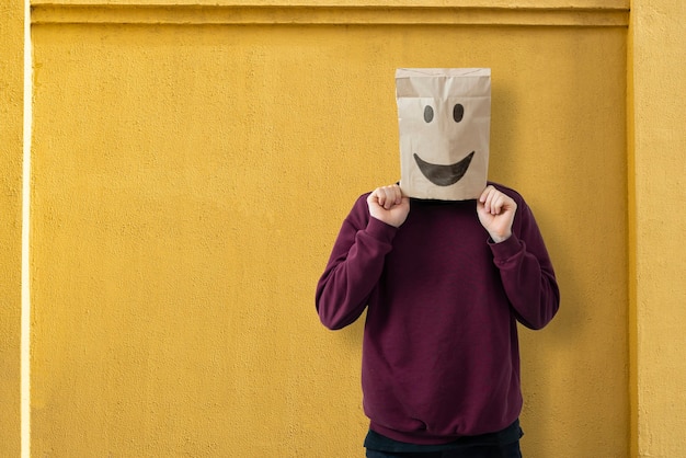 Una persona con una bolsa de papel en la cabeza con una sonrisa, feliz concepto de éxito