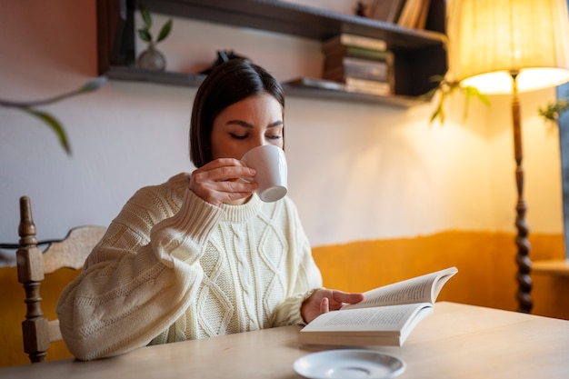 Foto persona en un café leyendo un libro mientras toma un café
