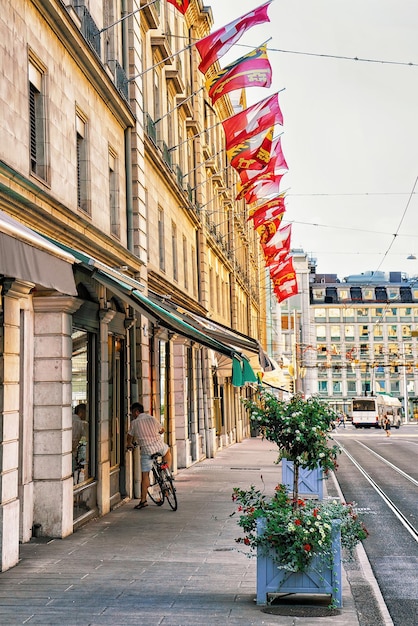 Persona y calle Corraterie con banderas suizas y de cantón en el centro de Ginebra, Suiza.