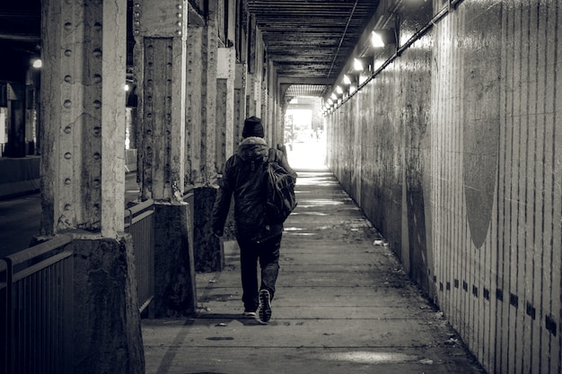 Una persona camina a través de un túnel oscuro en una gran ciudad, dirigiéndose hacia la luz.