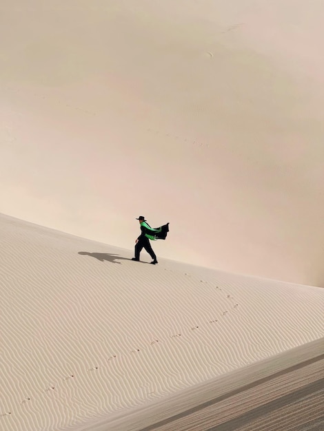 Foto una persona caminando en la arena con una bandera en la espalda.