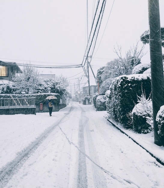 Una persona caminando en la nieve con un paraguas.