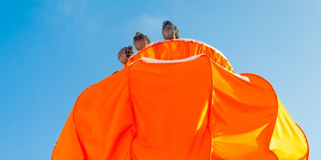 Una persona con una camisa naranja brillante mira hacia el cielo.